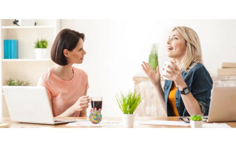 Unterhaltung Zwei Frauen in einer Unterhaltung am Tisch