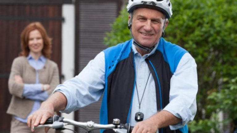Senioren Mobilität Senior mit Fahrrad und Fahrradhelm mit Frau im Hintergrund