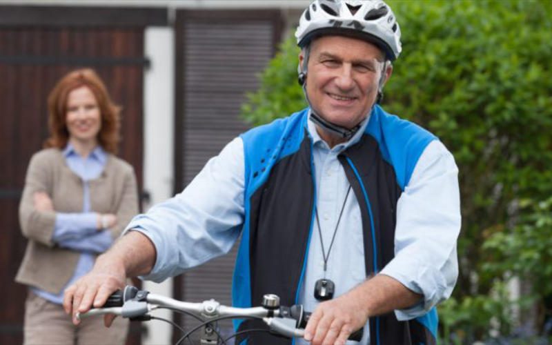 Senioren Mobilität Senior mit Fahrrad und Fahrradhelm mit Frau im Hintergrund