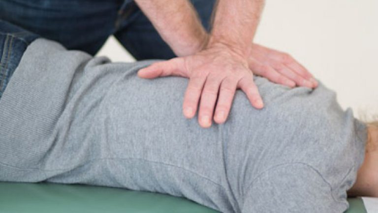 Zwei überkreuzte Hände drücken auf den Rücken einer liegenden Person