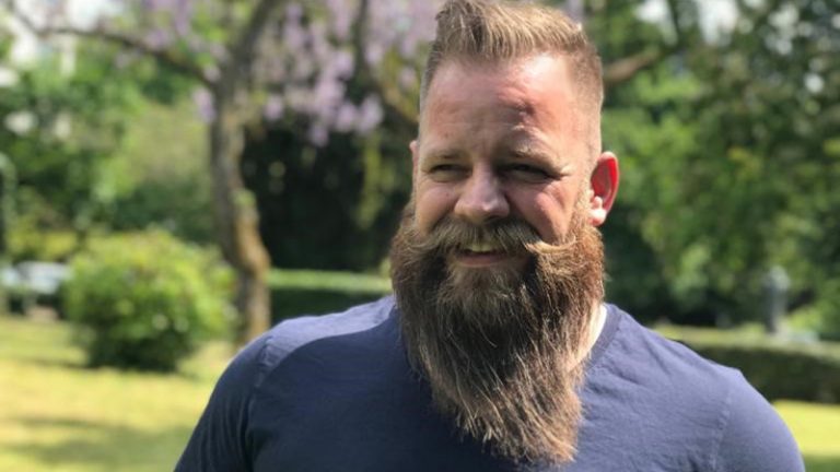 Edgar Ehlers Agile Coach Ein Mann mit langem Bart und blauem Shirt steht in einem Park und lächelt