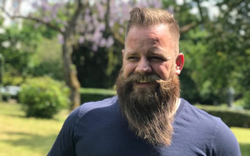Edgar Ehlers Agile Coach Ein Mann mit langem Bart und blauem Shirt steht in einem Park und lächelt