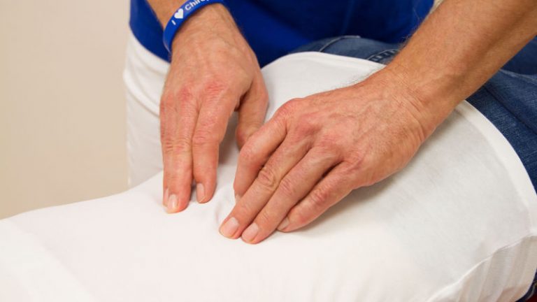 Zwei Hände untersuchen einen Rücken