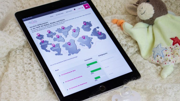 Auf einer weißen Wolldecke liegen ein Schnuller, ein Kuscheltier-Esel und ein Tablet mit der aufgeschlagenen Seite 4kids.