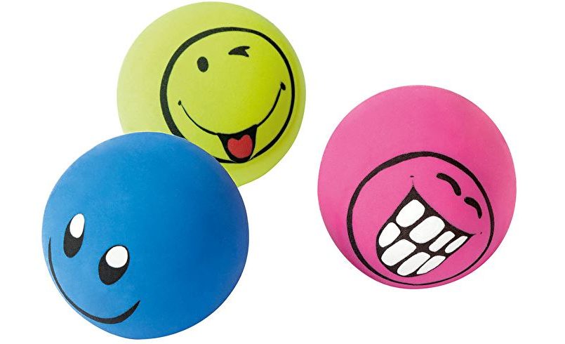 Drei Bälle mit lachenden Gesichtern in blau, gelb und pink