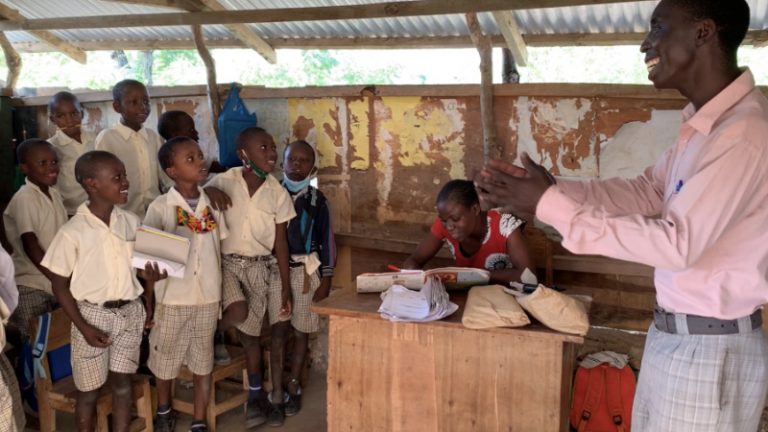Schüler der SEAHORSE SCHOOL in Kenya im Klassenzimmer hören einem Man in Pinken Hemd zu.