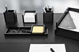 Büromaterial in schwarzen Kästchen auf einem Schwarzen Tisch.