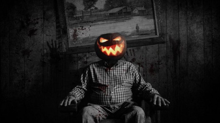 Schwarz-weisses Halloween Foto mit einem Mann der auf einem Sessel sitzt und als Kopf ein leuchtendes Halloween Kürbis hat.