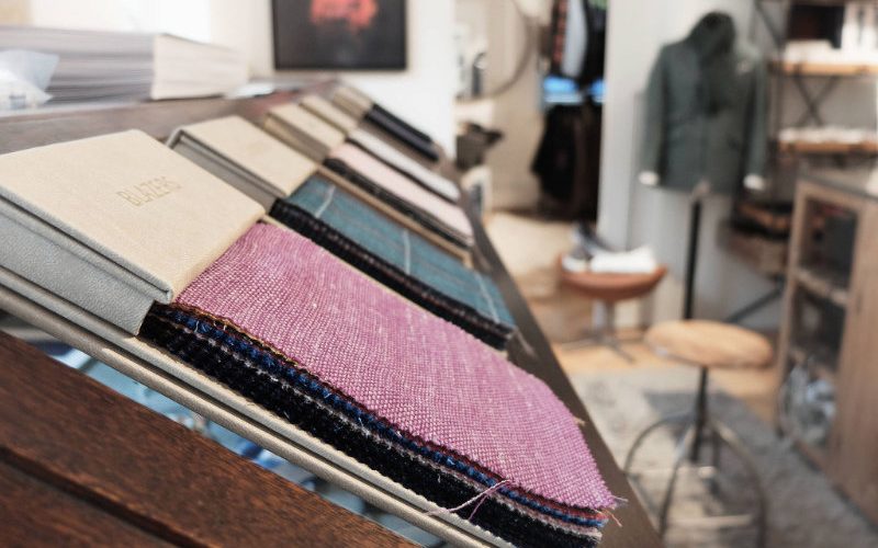 Stoffe Unterschiedliche Stoffe in einem Schneiderraum liegen an einem Tisch aus Holz.