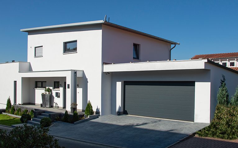 Izodom_Kassel_kleiner 7 Ein Weisses Haus mit flachen Dach und einer grauen Garage