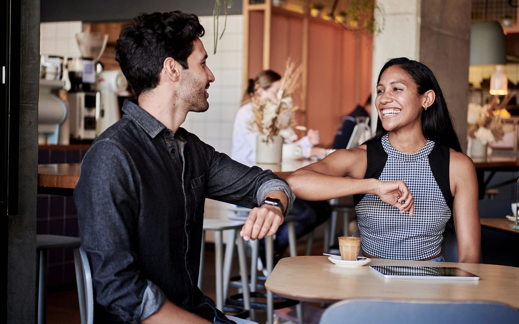 KingsmanHouse_Dating_unsplash_docusign_300dpi Ein Mann im jeans Hemd und eine Frau im karierten Oberteil begrüßen sich mit Ellenbogen