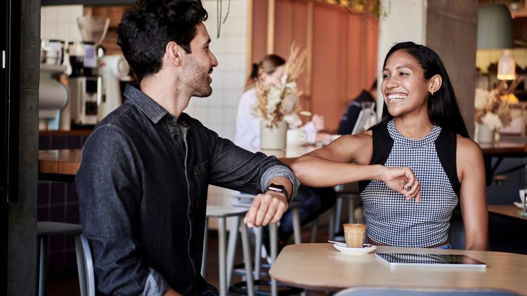 KingsmanHouse_Dating_unsplash_docusign_300dpi Ein Mann im jeans Hemd und eine Frau im karierten Oberteil begrüßen sich mit Ellenbogen