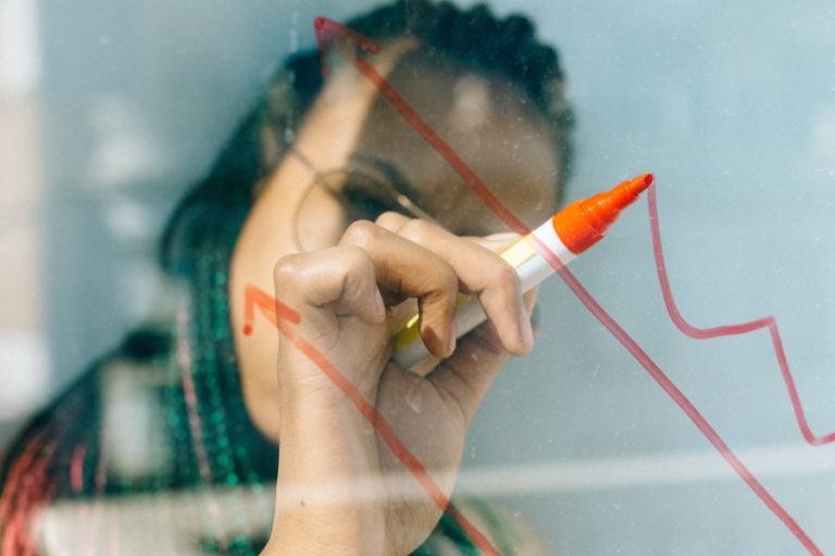 Eine Frau mit Brille schreibt mit einem roten Stift auf das Glass