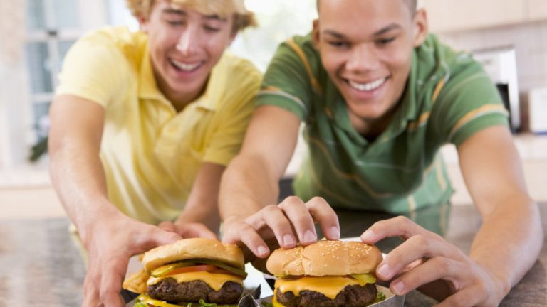 Teenagers,Eating,Burgers Zwei lächelnde Jungs die Burgers essen.