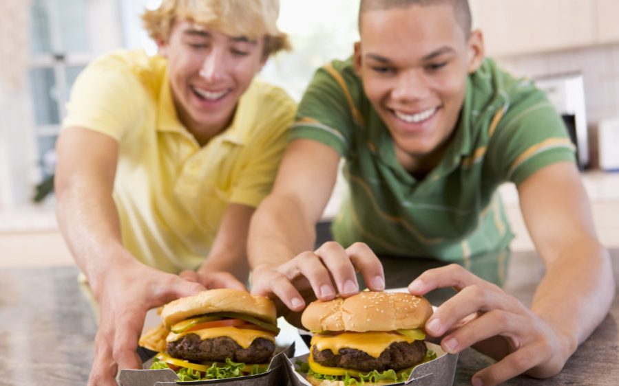 Teenagers,Eating,Burgers Zwei lächelnde Jungs die Burgers essen.