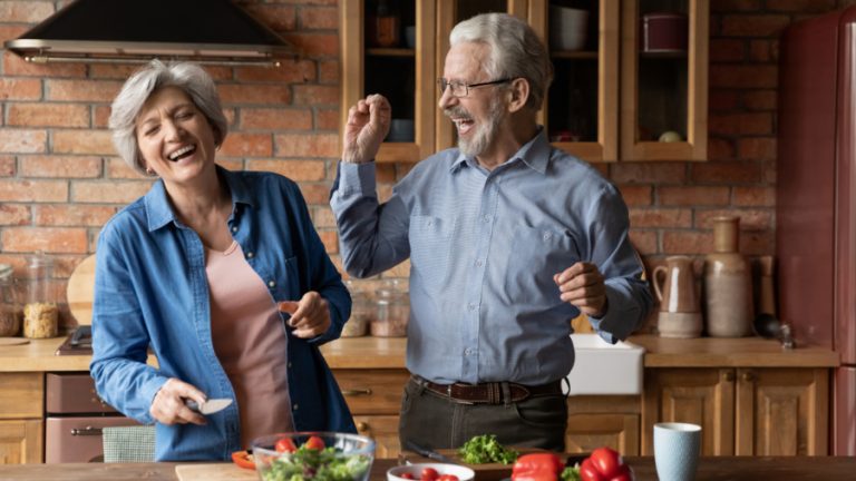 Ein glückliches Paar mittleren Alters, das beim Kochen in der Küche Spaß hat.