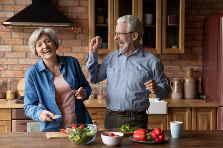 Ein glückliches Paar mittleren Alters, das beim Kochen in der Küche Spaß hat.