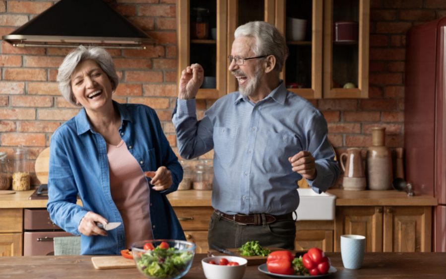 Ein glückliches Paar mittleren Alters, das beim Kochen in der Küche Spaß hat.