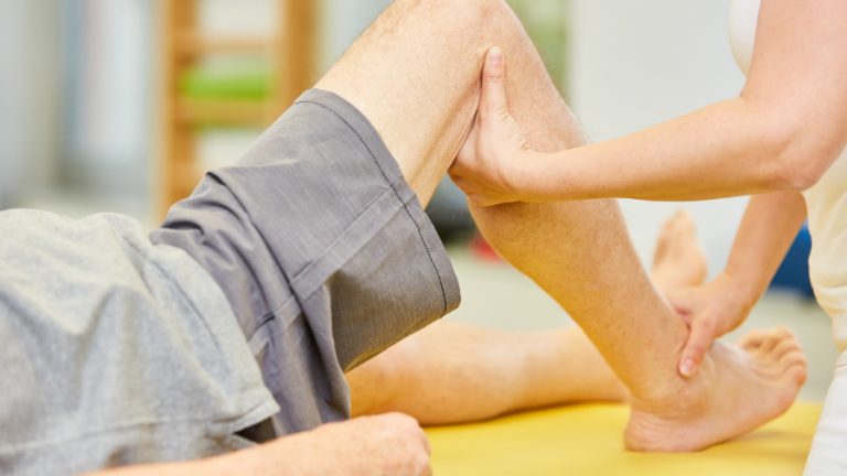 BildreAdobeStock: 354539496 / Thema: Chronische Schmerzen erfolgreich behandeln durch multimodale Schmerztherapie Physiotherapeutin behandelt Kniegelenk mit Osteopathie als Methode der Alternativmedizin