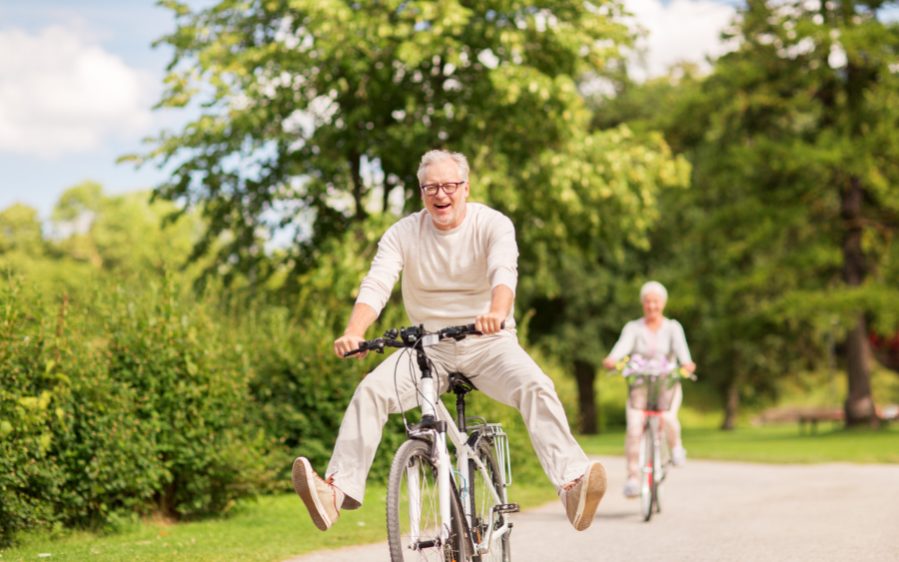 Stressreduktion gegen das Altern aktives Alter, Menschen und Lifestyle-Konzept - glückliches Seniorenpaar beim Fahrradfahren im Sommerpark