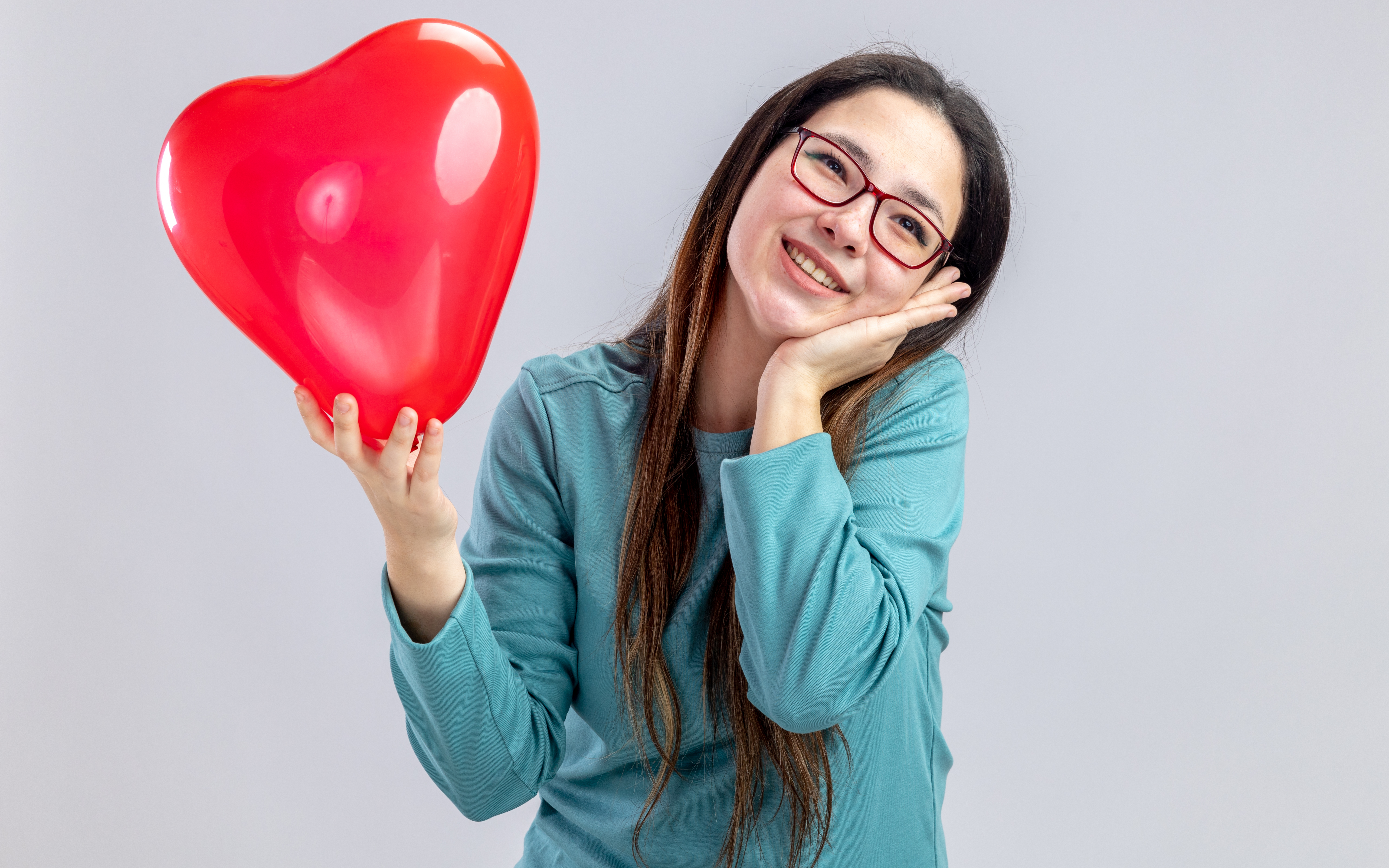 Eine lächelnde Frau hält einen roten Ballon in Form eines Herzes