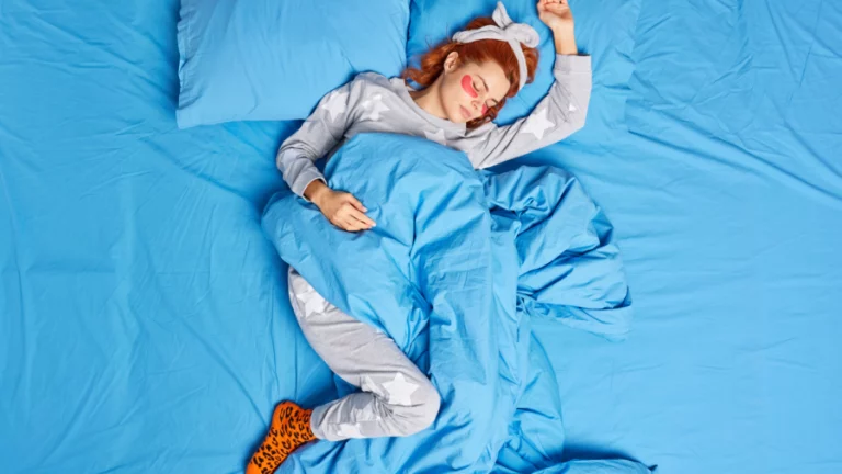 oben-ansicht-der-entspannten-rothaarigen-frau-die-im-pyjama-stirnband-gekleidet-ist-vor-dem-schlafengehen Schlafende junge Frau in einem blauen Bett, die Pyjama und Stirnband trägt