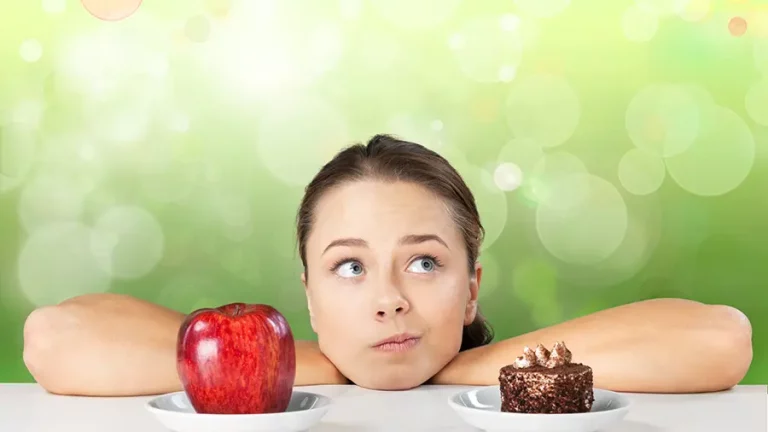 attraktive-junge-frau-trifft-ihre-wahl-zwischen-apfel-und-kuchen-gesundes-lifestyle-konzept_900x600 Frau die sich auf einen Tisch stützt und nachdenklich in die Luft schaut. Vor ihr befindet sich ein Apfel und ein Stück Kuchen