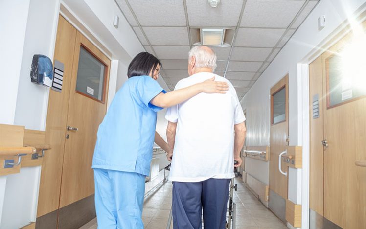 Asian female doctor reassuring mature elderly man with walker. M